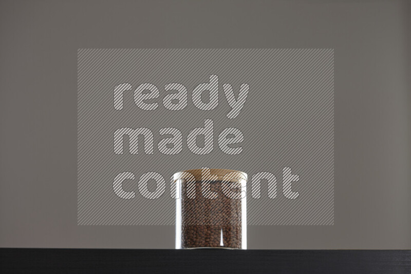 Brown lentils in a glass jar on black background