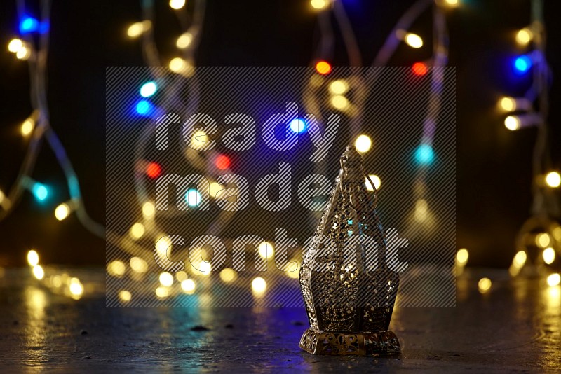 A golden lantern with fairy light in a dark setup