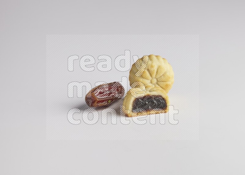 Two Pieces of Maamoul filled with date one of them is cut direct on white background