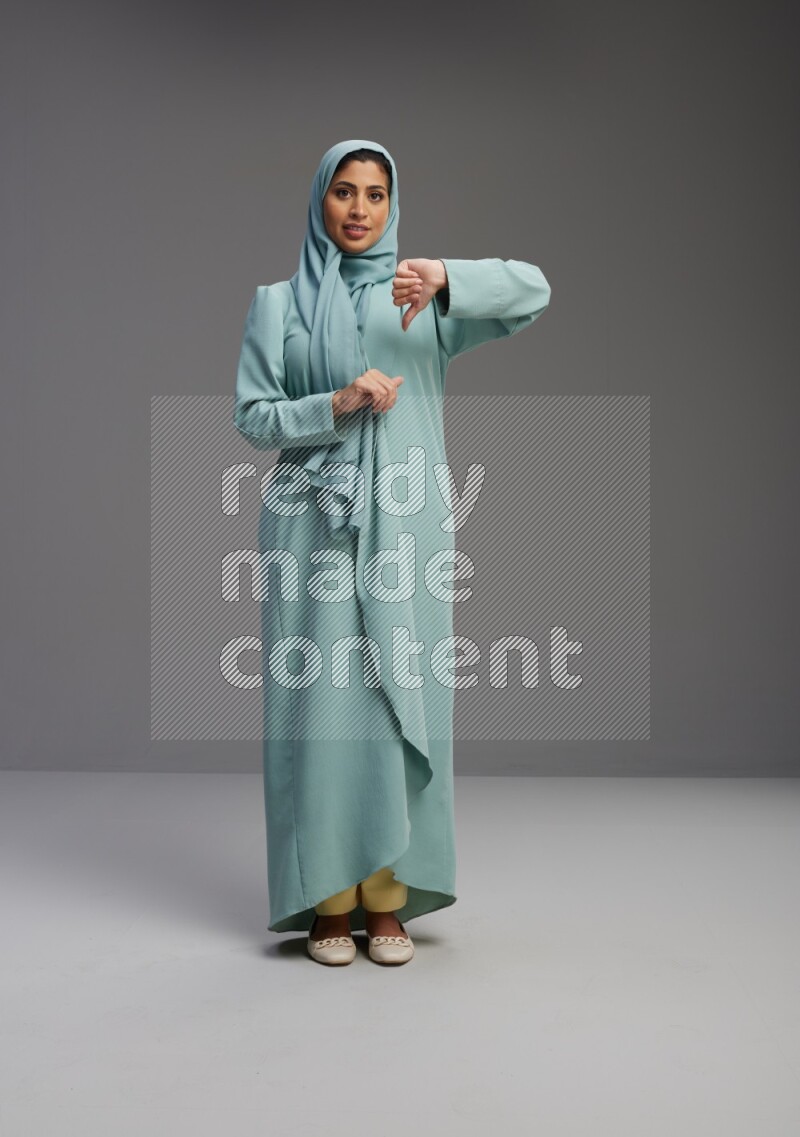 Saudi Woman wearing Abaya standing interacting with the camera on Gray background