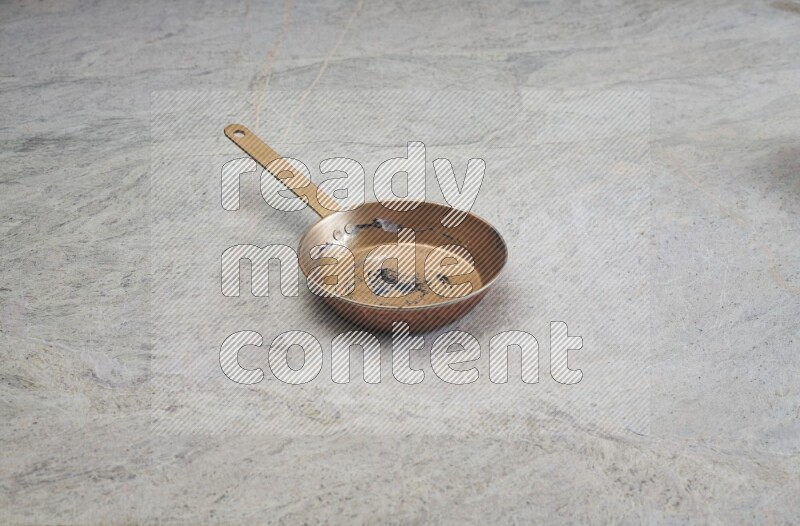 A small copper pan on grey marble background