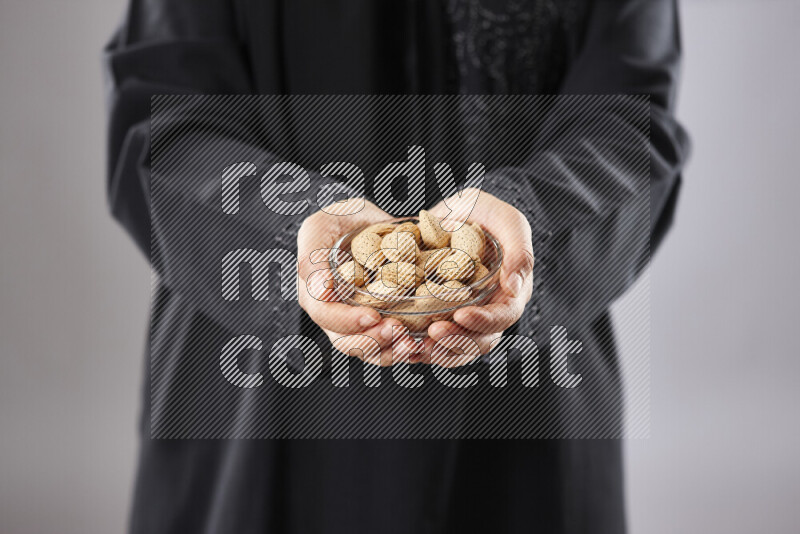 Woman in abaya holding different kinds of nuts in different positions