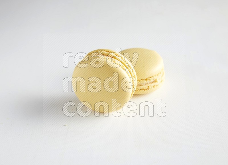 45º Shot of two Yellow Vanilla macarons on white background