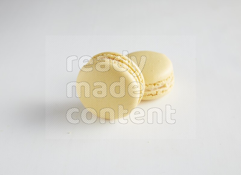 45º Shot of two Yellow Vanilla macarons on white background
