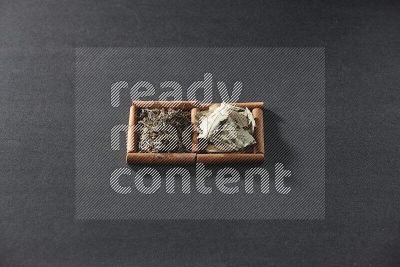 2 squares of cinnamon sticks full of bay laurel leaves and dried basil on black flooring