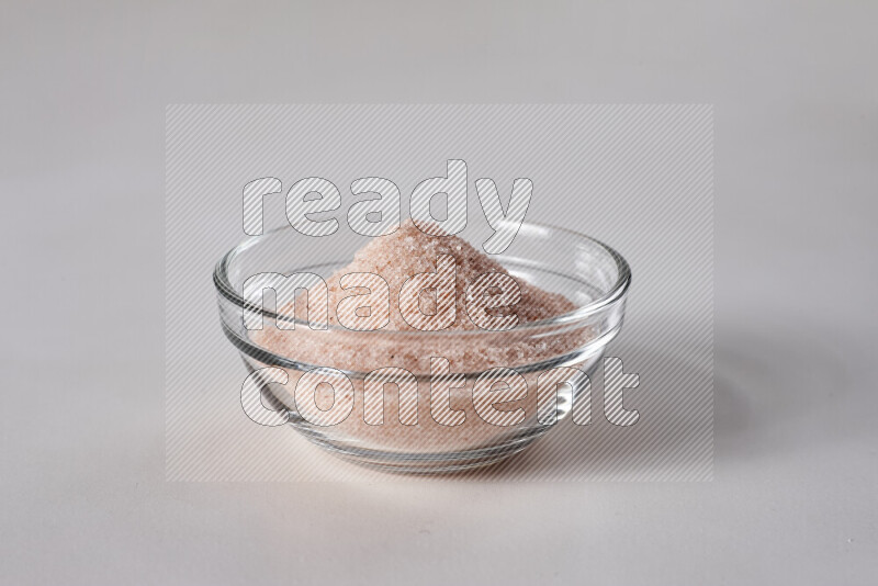 A glass bowl full of fine himalayan salt on white background