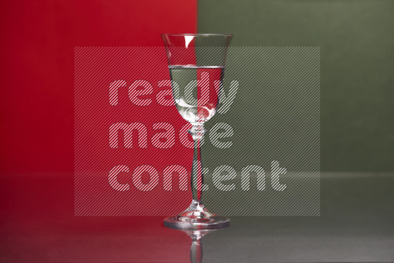 The image features a clear glassware filled with water, set against red and dark green background