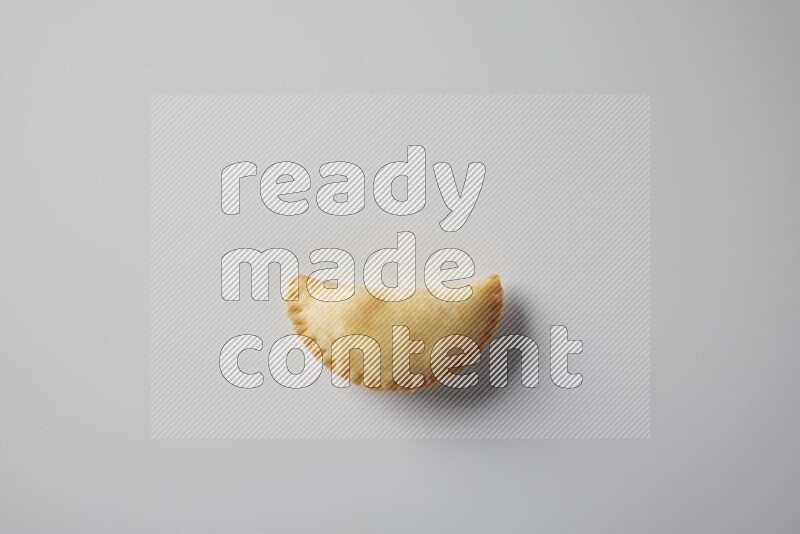 One fried sambosa from a top angle on a white background