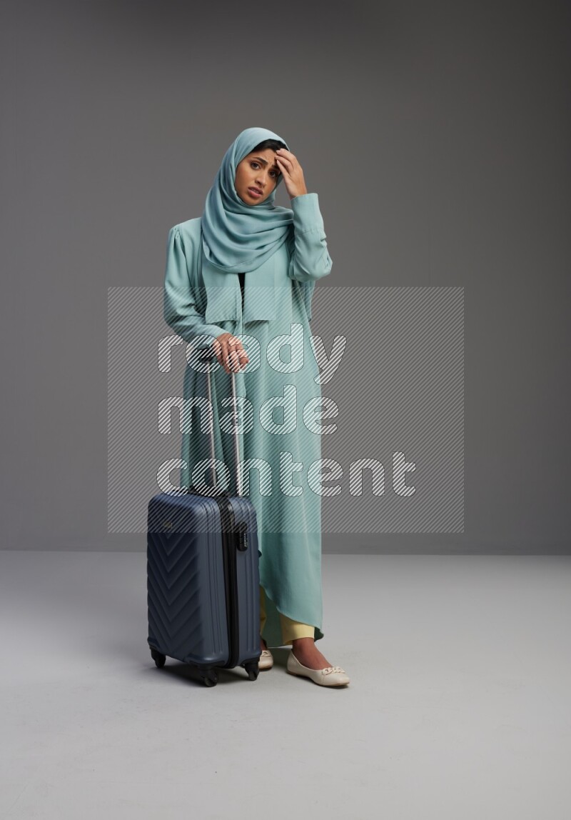 Saudi Woman wearing Abaya standing holding Travel bag on Gray background