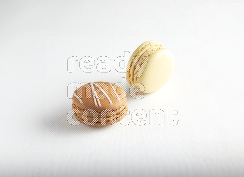 45º Shot of of two assorted Brown Irish Cream, and Yellow Vanilla macarons on white background