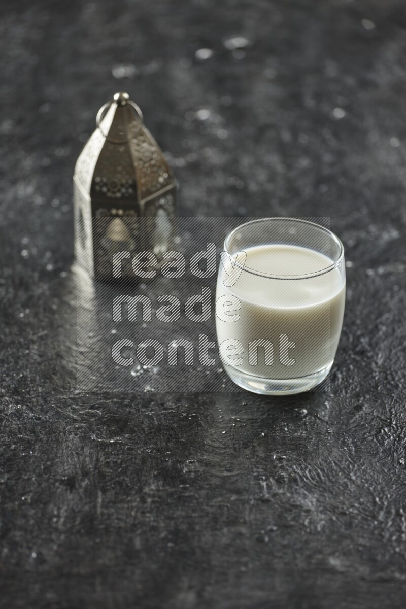 فانوس فضي مع مشروبات مختلفة وتمر ومكسرات وسبحة صلاة وقرآن على خلفية سوداء