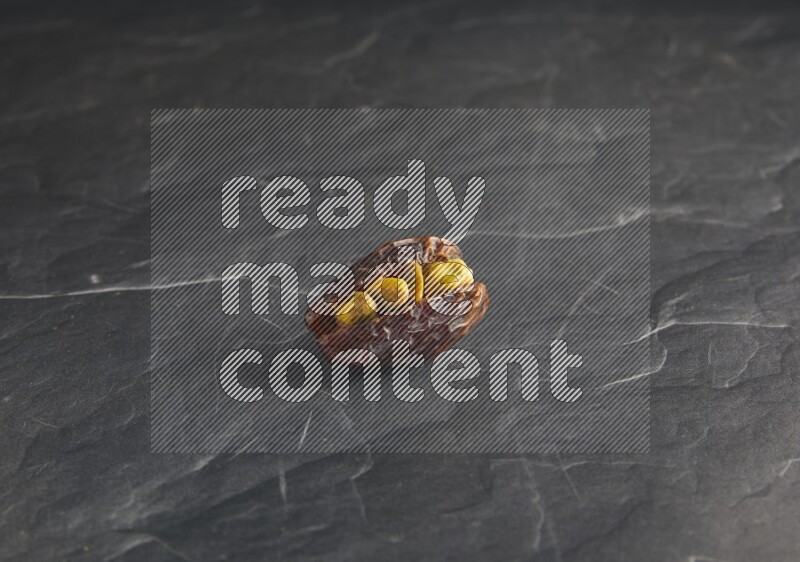 pistachios stuffed madjoul date on a black textured background