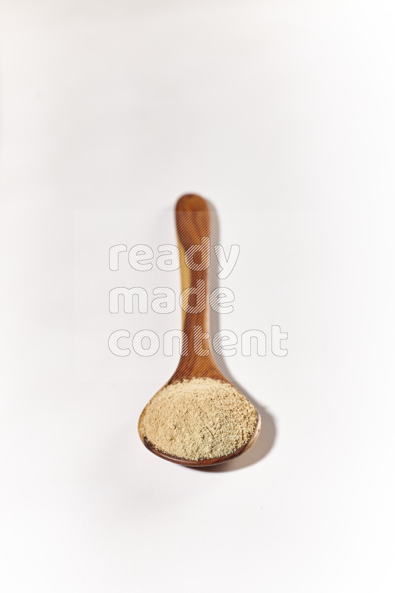 A wooden ladle full of ground ginger powder on white background