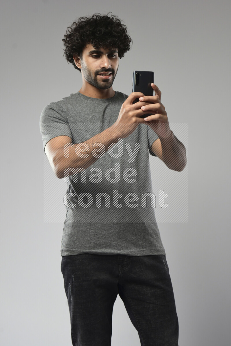 A man wearing casual standing and shooting with his phone on white background
