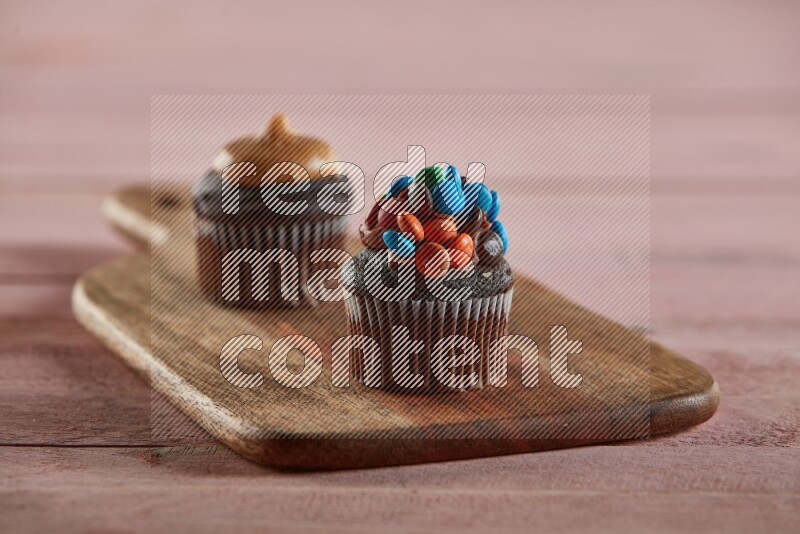 Chocolate mini cupcake topped with m&ms on a wooden board