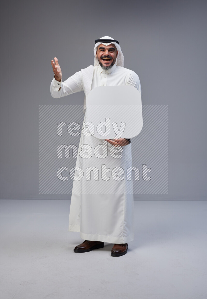 Saudi man Wearing Thob and white Shomag standing holding social media sign on Gray background