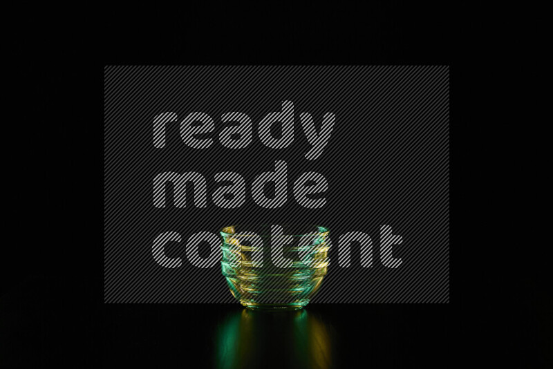 Glassware with rim light in green and yellow against black background