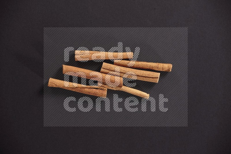 Cinnamon sticks stacked on black flooring