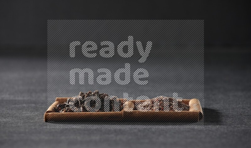 مربعان من أعواد القرفة ممتلئان ببذور الكتان والقرنفل علي خلفية سوداء