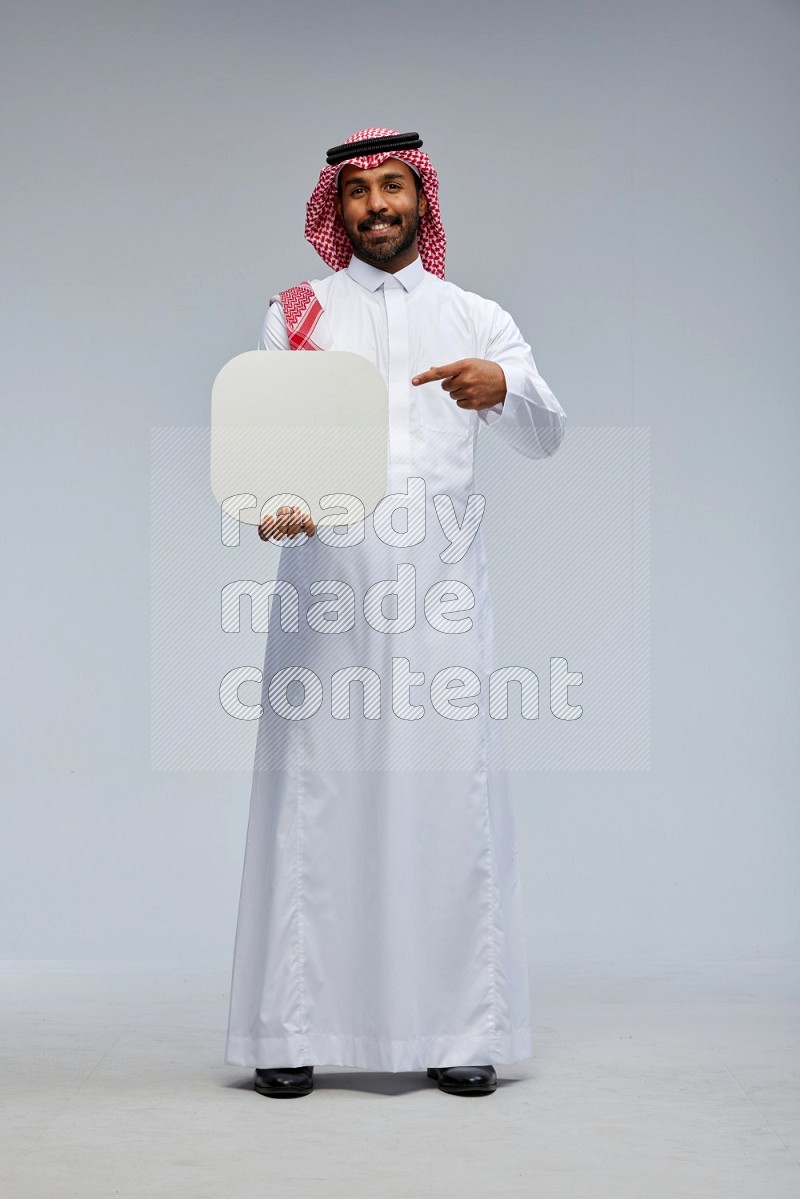 Saudi man Wearing Thob and shomag standing holding social media sign on Gray background