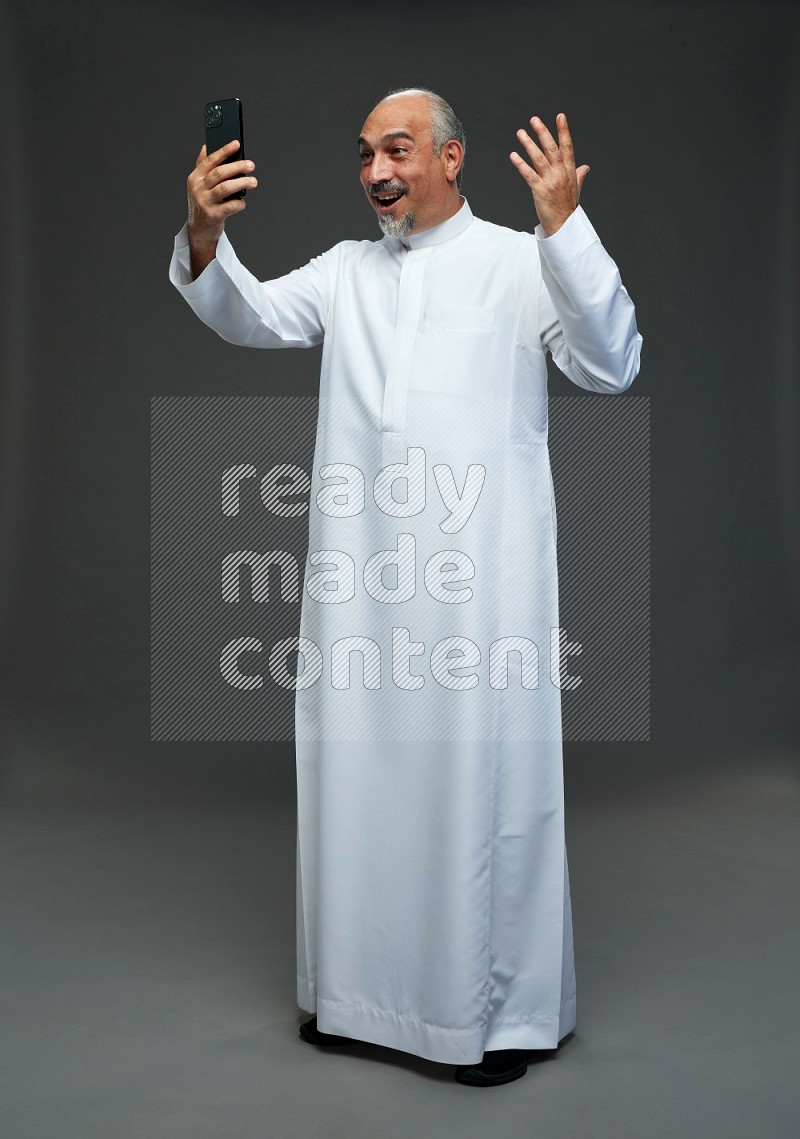 Saudi man without shomag Standing taking selfie on gray background