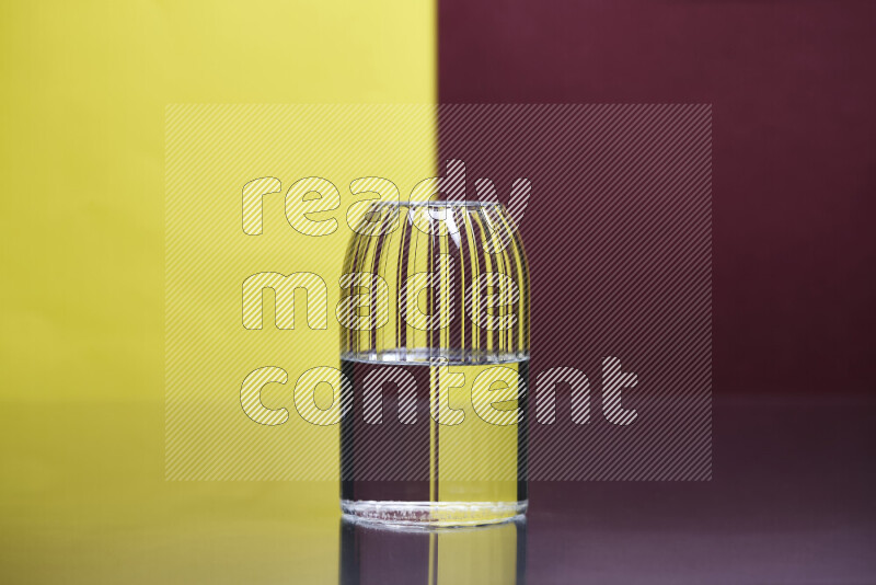 The image features a clear glassware filled with water, set against yellow and dark red background
