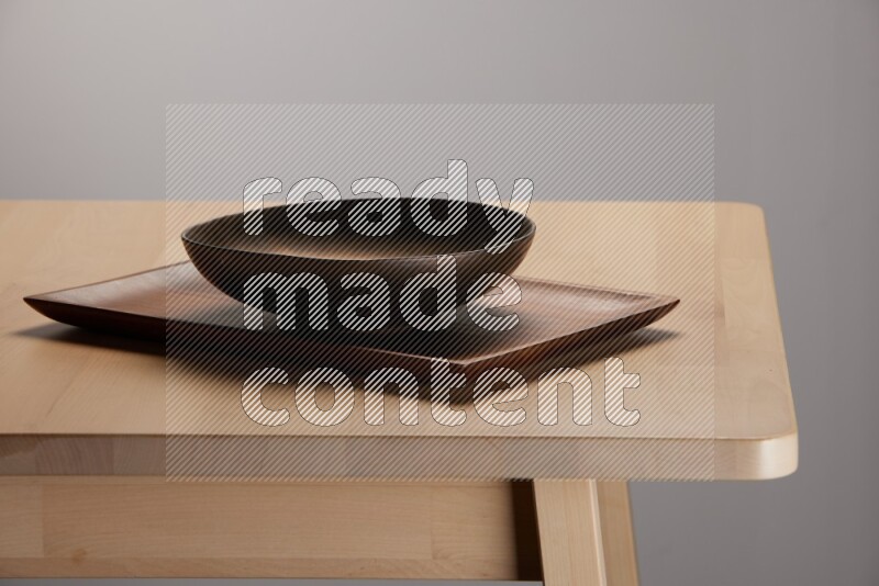 brass plate placed on a rectangular wooden tray on the edge of wooden table
