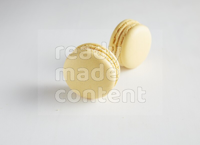 45º Shot of two Yellow Vanilla macarons on white background