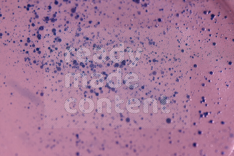 لقطات مقربة لقطرات ألوان مائية زرقاء على سطح الزيت على خلفية وردية
