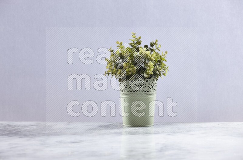 Artificial plant in green decorative pot on grey marble background