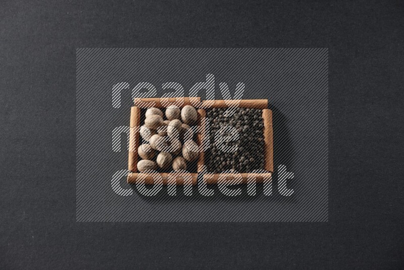 2 squares of cinnamon sticks full of nutmegs and black peppers on black flooring