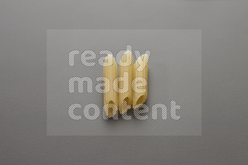 Mini penne pasta on grey background