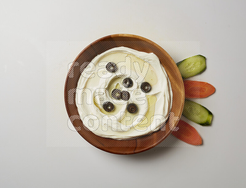 Lebnah garnished with sliced olives in a wooden plate on a white background