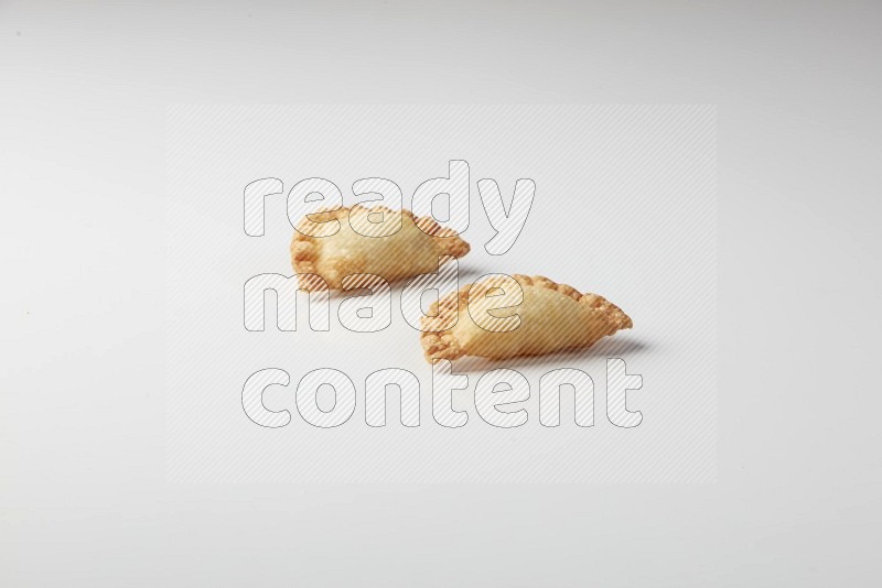 Two fried sambosas on a white background