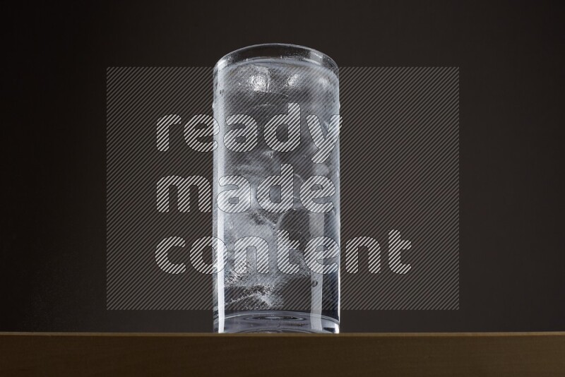 Low angle shot of a glass of water and ice on grey background