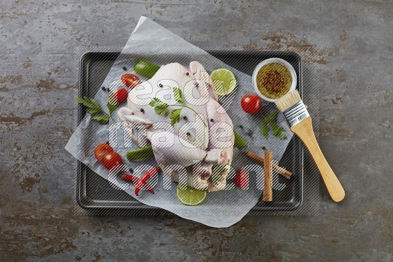 whole raw chicken on an oven trey direct on a rustic grey background