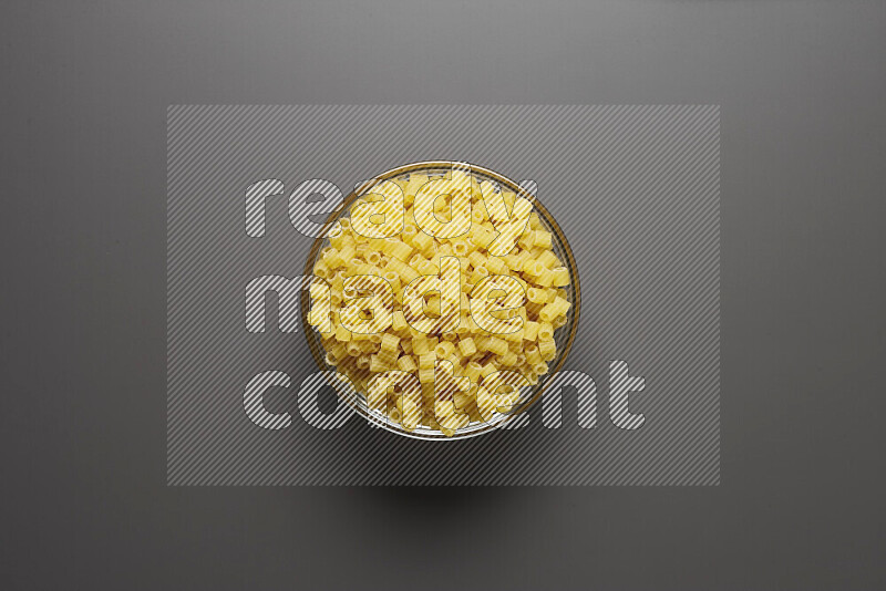 Small rings pasta in a glass bowl on grey background