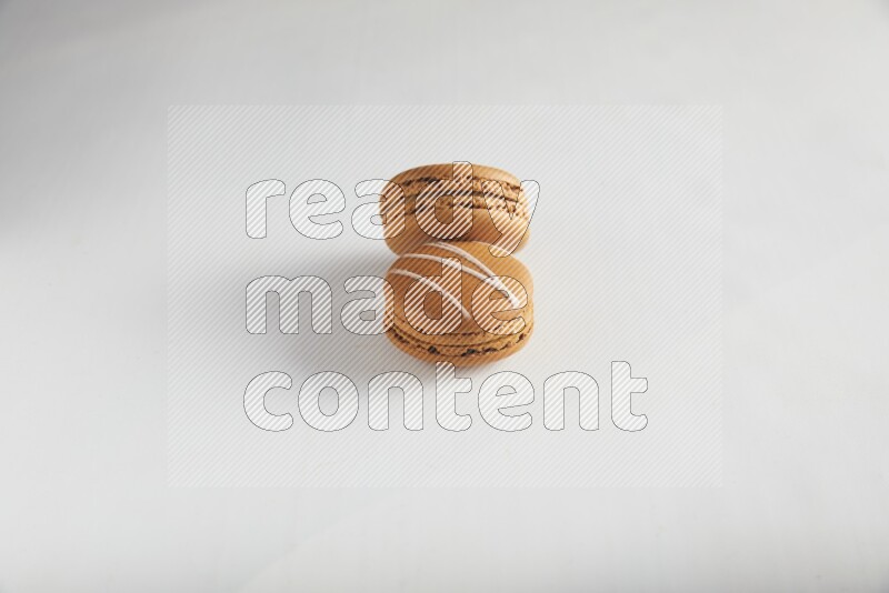 45º Shot of of two assorted Brown Irish Cream, and Brown Maple Taffy macarons  on white background
