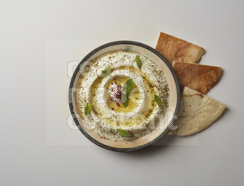 Lebnah garnished with zaater, mint & sumak in a pottery plate on a white background