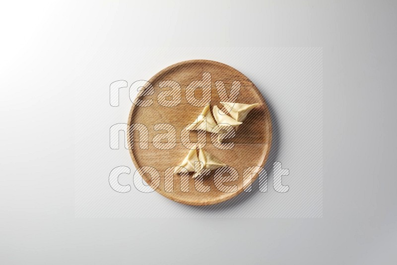 Five Sambosas on a wooden round plate on a white background