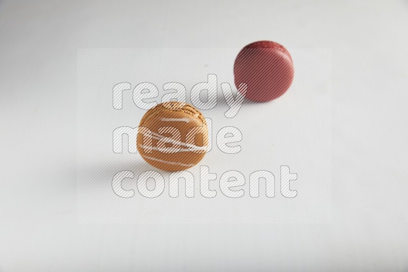45º Shot of of two assorted Brown Irish Cream, and Red Velvet macarons on white background