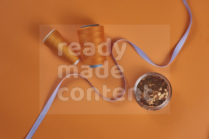 A purple collection of sewing and tailoring tools arranged on a orange background