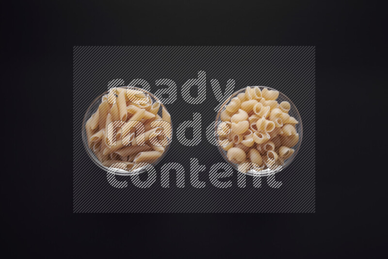 Different pasta types in glass bowls on black background