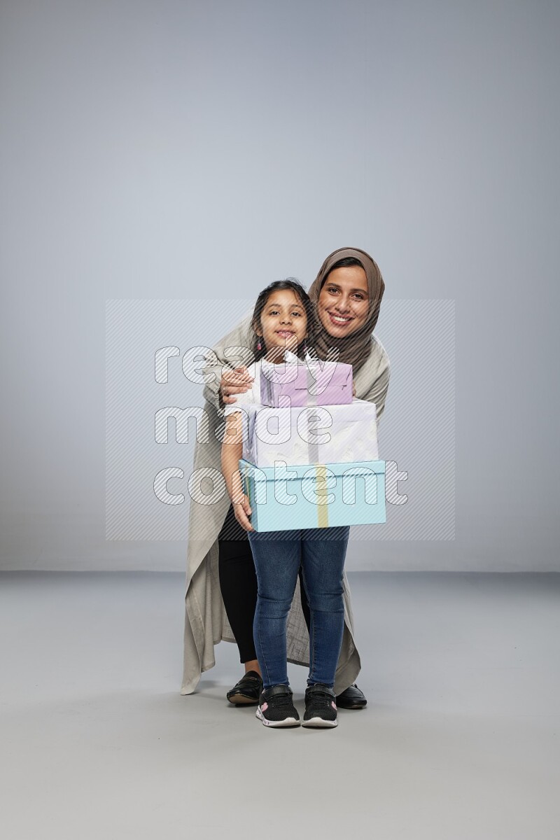 A girl giving a gift to her mother on gray background