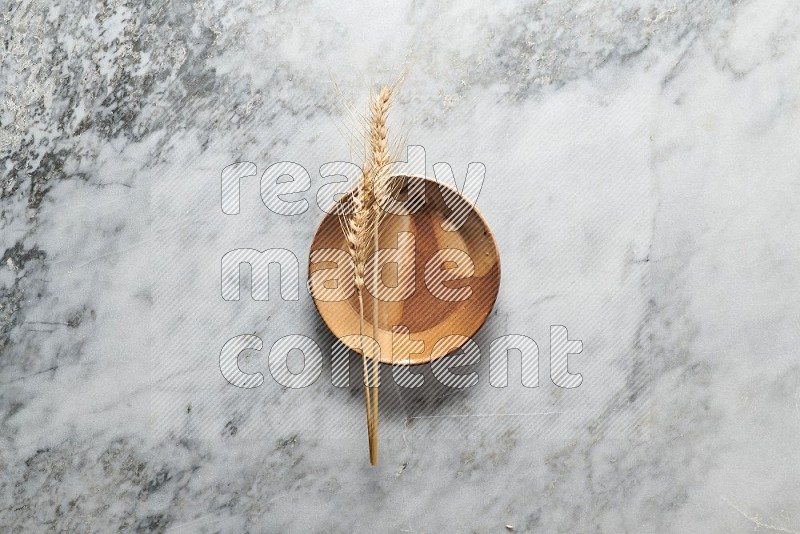 Wheat stalks on Multicolored Pottery Plate on grey marble flooring, Top view