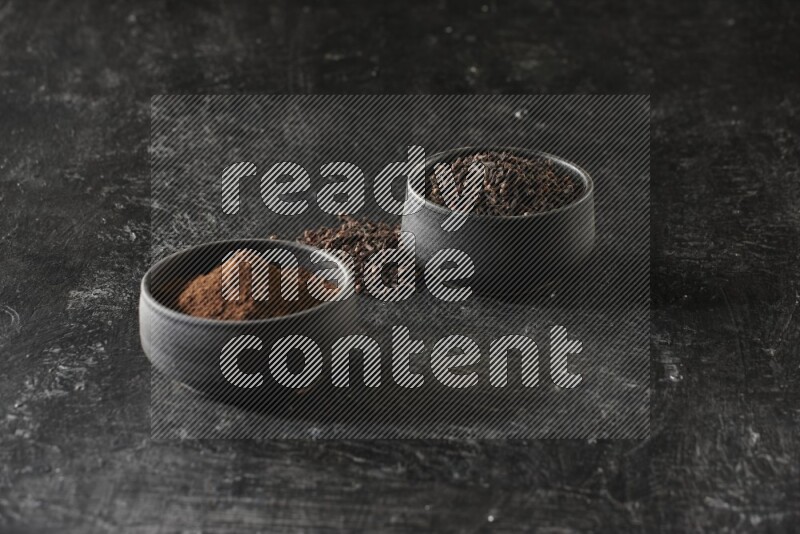 وعاءين من الفخار الأسود أحدهما ممتلئي بحبوب القرنفل والآخر ممتلئ ببودرة القرنفل على خلفية سوداء