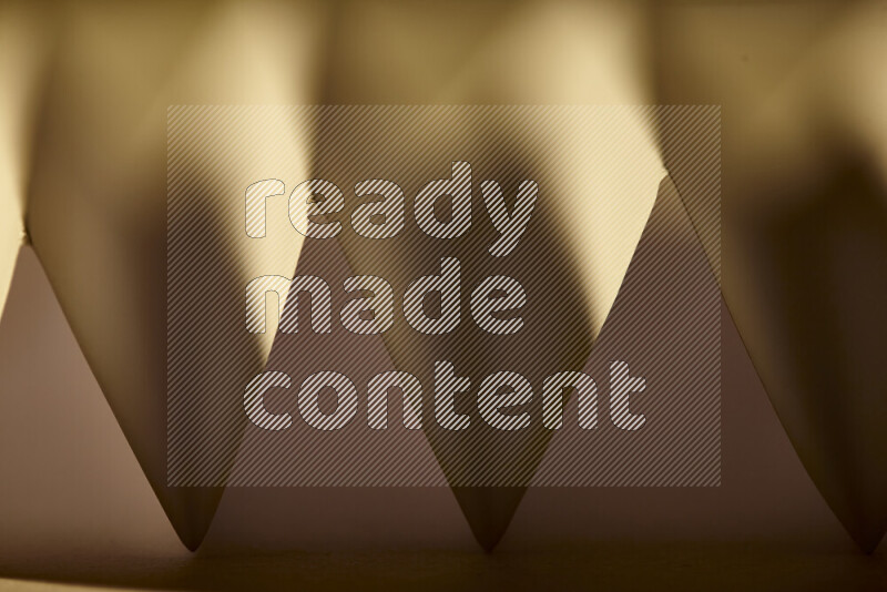 A close-up abstract image showing sharp geometric paper folds in warm gradients
