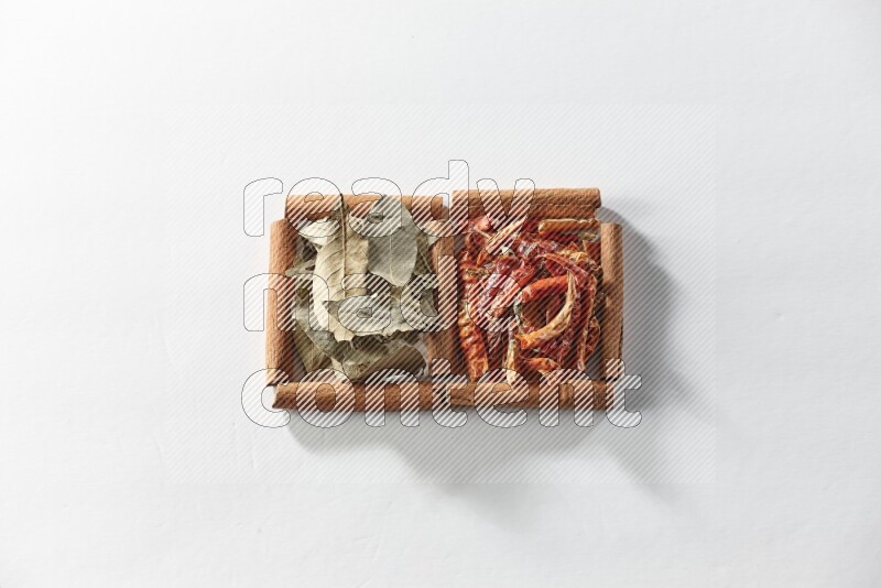 2 squares of cinnamon sticks full of dried red chilis and bay laurel leaves on white flooring