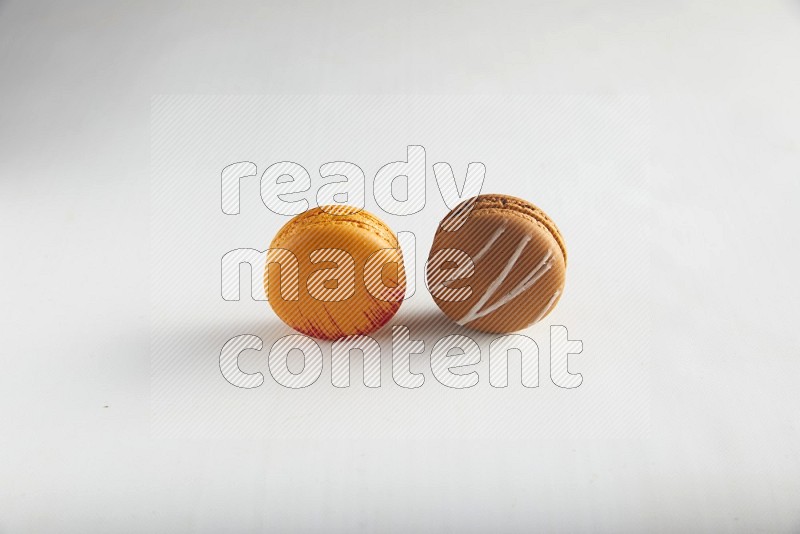 45º Shot of of two assorted Brown Irish Cream, and Orange Exotic macarons on white background