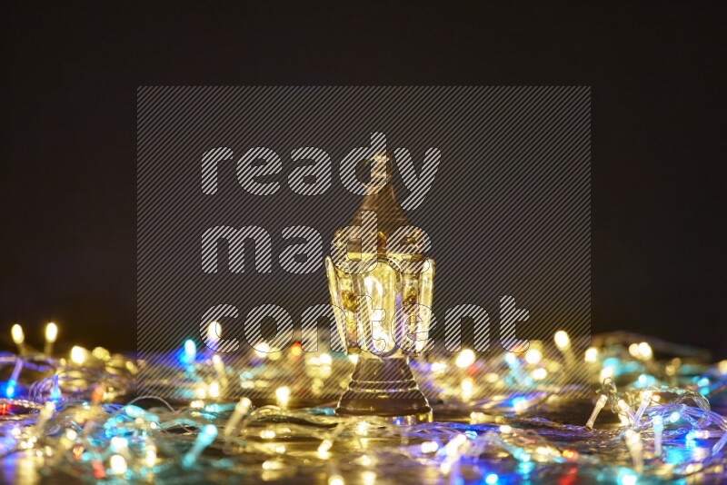 A traditional ramadan lantern surrounded by glowing fairy lights in a dark setup